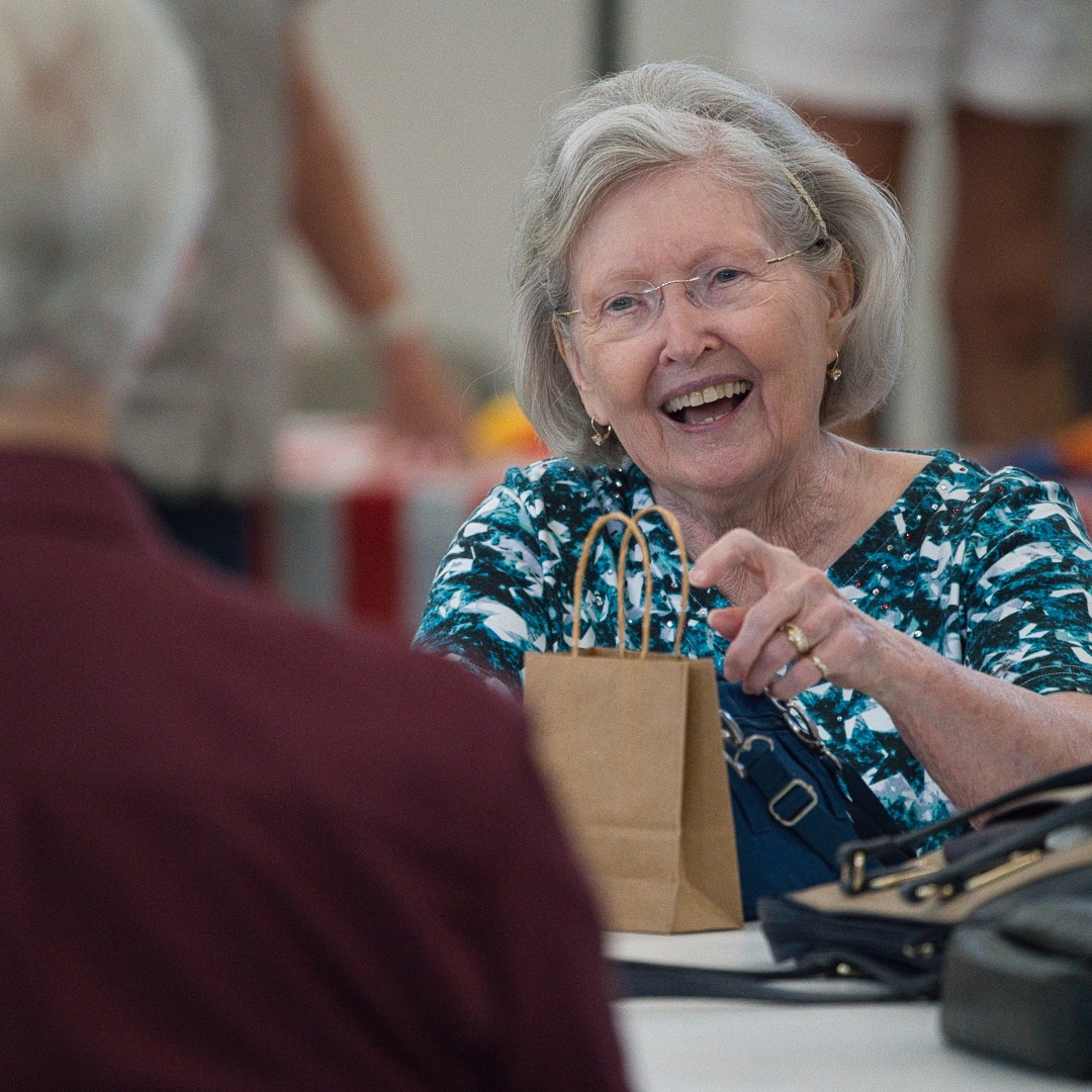 Senior members of New Hope Clovis gathered around tables, enjoying a monthly senior lunch event, with plates of food and beverages visible, sharing smiles and conversations, showcasing the vibrant senior community at a Christian Church in Clovis.