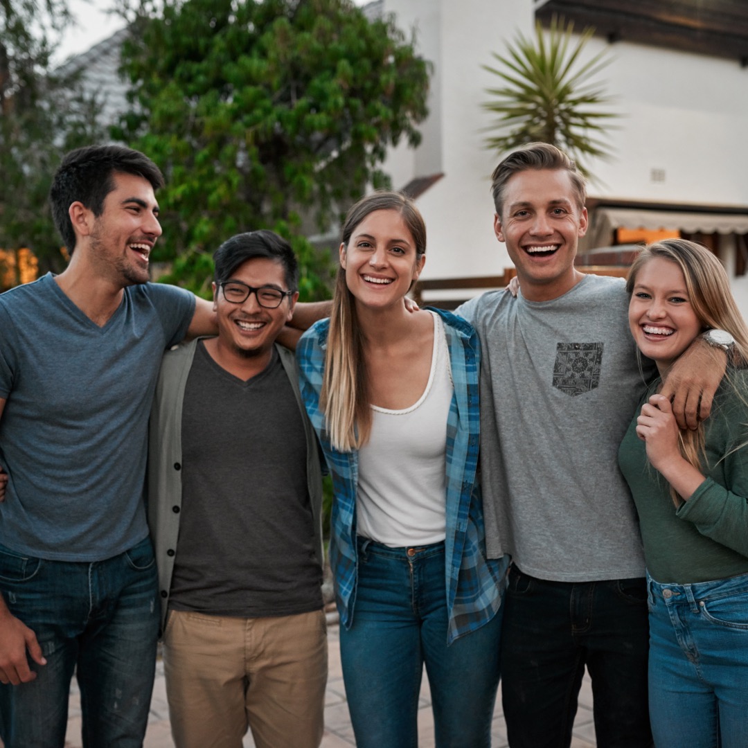 A diverse group of young adults from New Hope Clovis smiling outside the facility after a Bible study session, expressing joy and camaraderie, part of the active Christian community in Clovis.